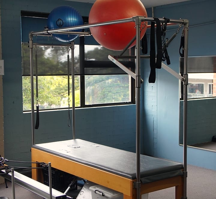 A Pilates trapeze table beside the window in the rehabilitation studio